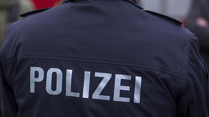 "Polizei" steht auf der Uniform eines Polizisten.