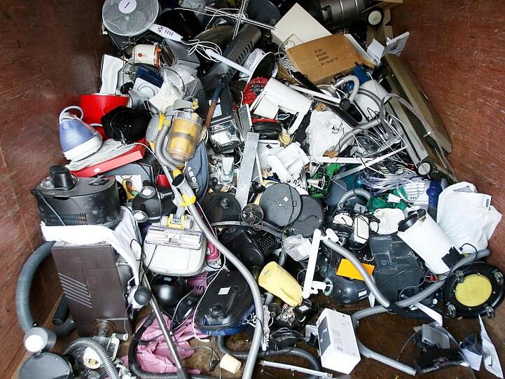 Ausrangierte Haushaltsgeräte und andere Elektrogeräte in einem Sammelbehälter für Elektroschrott.