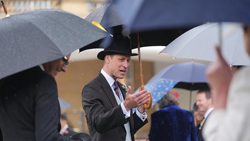Trotz des starken Regens zeigt er sich heiter bis sonnig: Prinz William (ein paar Kilo hat er abgenommen) spricht mit Gästen während der Garten-Party vorm Buckingham-Palast. Trotz des starken Regens zeigt er sich heiter bis sonnig: Prinz William (ein paar Kilo hat er abgenommen) spricht mit Gästen während der Garten-Party vorm Buckingham-Palast.