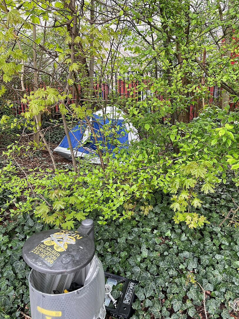 Hinter diesem Mülleimer hat jemand ein Zelt aufgebaut. Hinter diesem Mülleimer hat jemand ein Zelt aufgebaut.