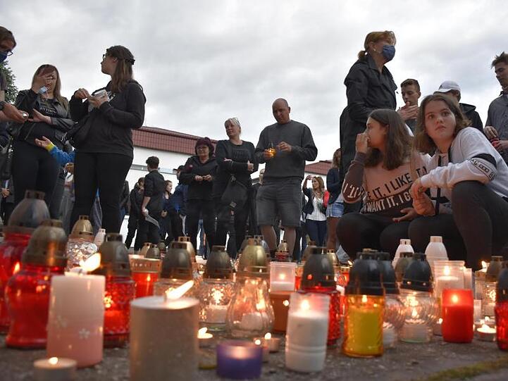 Menschen zünden Kerzen vor der Schule im Ort Vrutky an.