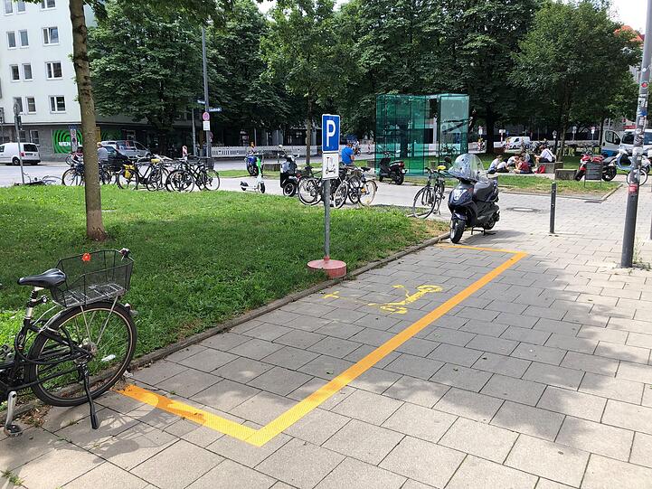 Auf dem Parkplatz steht kein E-Scooter, dafür aber im Hintergrund.