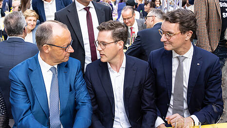Manuel Hagel nimmt zwischen Kanzler Merz (li.) und NRW-Ministerpräsident Wüst (re.) Platz