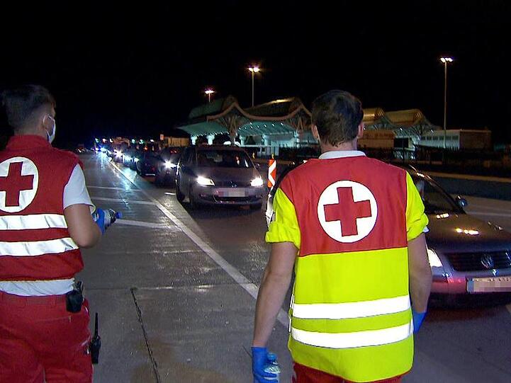 Mitarbeiter des Roten Kreuzes betreuen in der Nacht Autofahrer in einem kilometerlangen Stau bei der Einreise nach Österreich am Karawankentunnel.