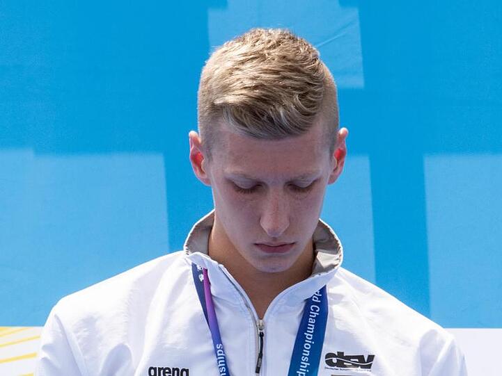 Florian Wellbrock hört bei der Siegerehrung der Schwimm-WM 2019 für seinen Sieg die Nationalhymne mit gesenktem Kopf. Foto: Bernd Thissen