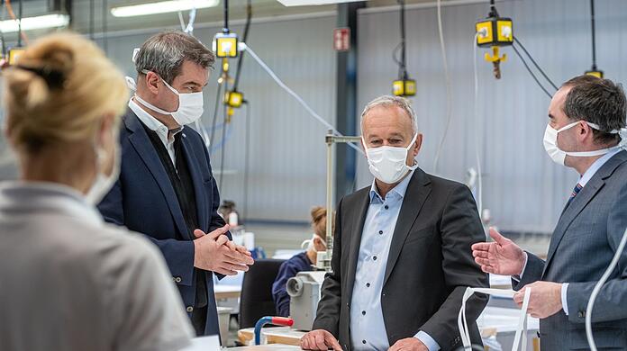 Geschäftsführer Reinhard Zettl und Hubert Aiwanger (Freie Wähler) stehen im April 2020 in der Produktionshalle des Automobilzulieferers Zettl, der auf die Produktion von Schutzmasken umgestellt hatte. Auch Ministerpräsident Markus Söder (CSU) machte sich damals vor Ort ein Bild. Der Auftrag wirft Fragen auf.