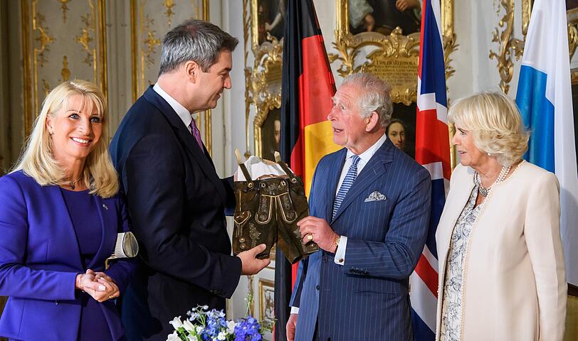 Söder überreicht Charles für Enkel Archie (Baby von Meghan und Harry) eine Lederhose.