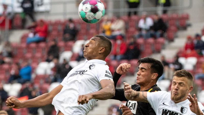 Felix Uduokhai (l-r), Reinier von Dortmund und Jeffrey Gouweleeuw von Augsburg im Kopfballduell um den Ball.
