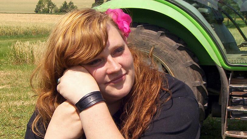Vanessa (24) aus Bayern schaut zu, während der fleissige Milchbauer Peter (26) auf dem Feld arbeitet.