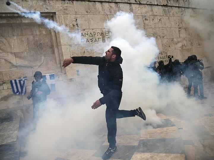 Straßenkampf in Athen: Ein Demonstrant wirft eine Tränengasgranate auf Bereitschaftspolizisten nahe dem Parlamentsgebäude.