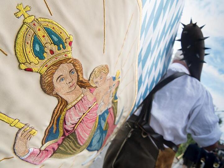 Ein Mann eine Marien-Fahne beim großen Trachtenfestzug. Foto: picture alliance / dpa/Symbolbild
