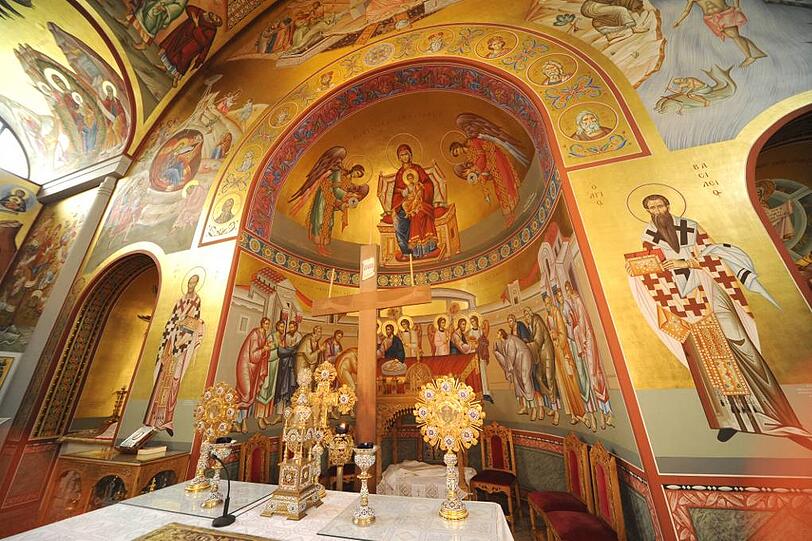 Das schlichte Holzkreuz vor aufwendiger Ikonenmalerei: die Innenausstattung steht in der Tradition griechisch-orthodoxer Kirchenkunst.