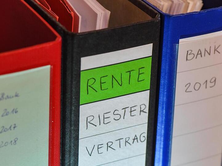 Ein Ordner mit der Aufschrift "Rente Riester Vertrag" steht zwischen anderen Aktenordnern.