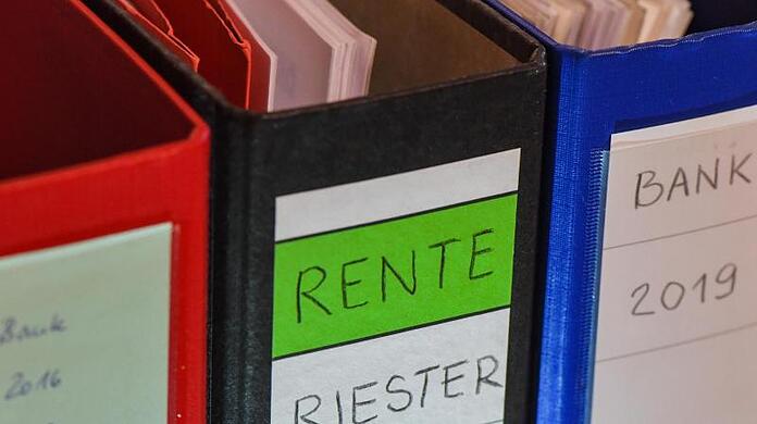 Ein Ordner mit der Aufschrift "Rente Riester Vertrag" steht zwischen anderen Aktenordnern. (Archivbild)