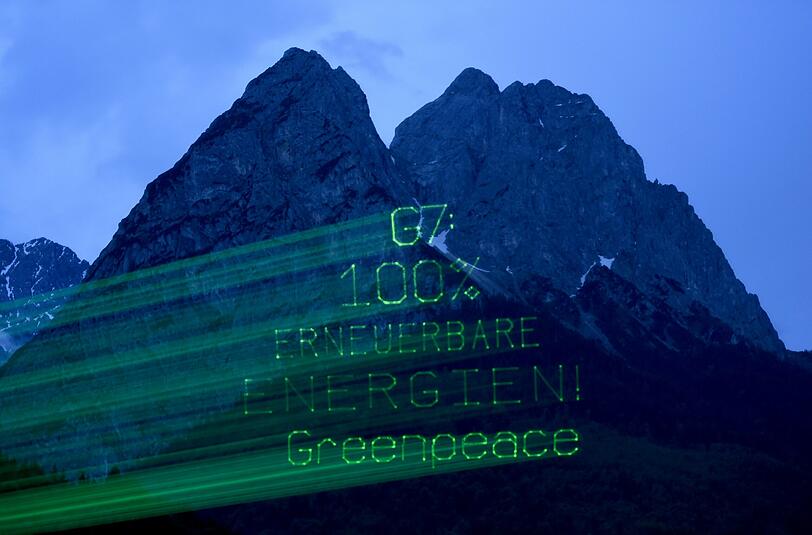 Protestaktion in der Morgendämmerung: Umweltaktivisten von Greenpeace haben am Montagmorgen eine Laser-Botschaft für die Gipfelteilnehmer an das Bergmassiv des Waxenstein projiziert.