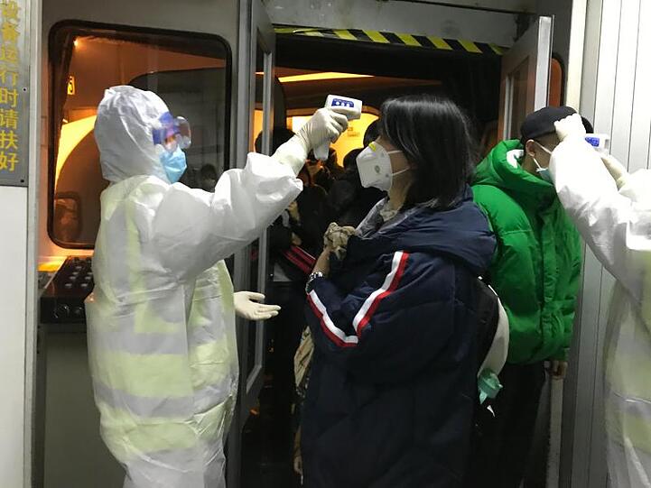 Gesundheitsbeamte kontrollieren am Flughafen von Peking die Körpertemperatur von Reisenden aus der Stadt Wuhan.