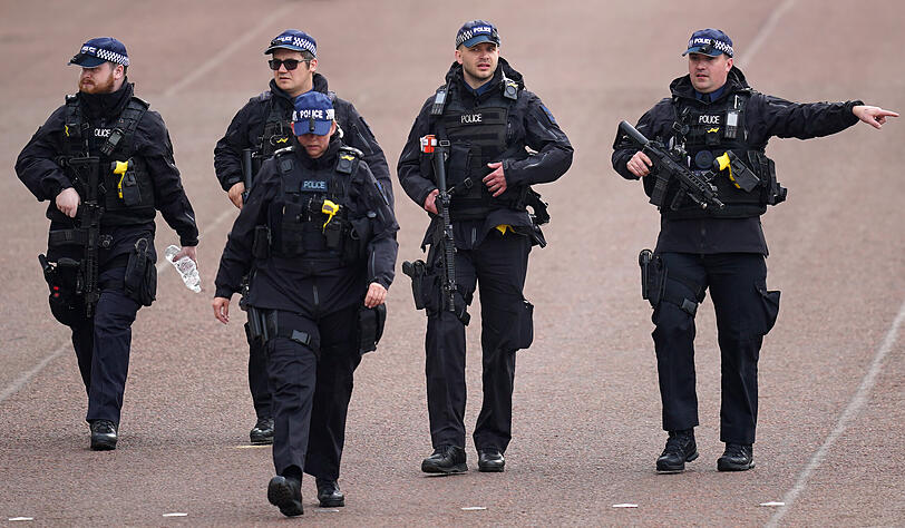 Bewaffnete Polizisten patrouillieren auf der Mall vor der Krönungszeremonie von König Charles III. und Königin Camilla.
