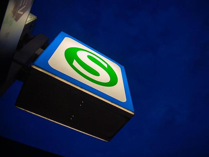 Ein S-Bahn-Schild hängt an der Station Hackerbrücke vor einem dunklen Morgenhimmel. Foto: Lino Mirgeler