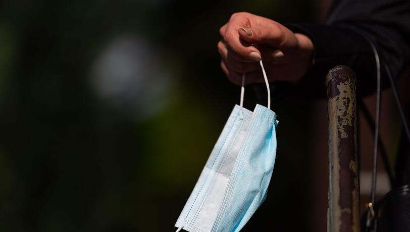Ein Frau hält ihren Mund-Nasen-Schutz in der Hand.