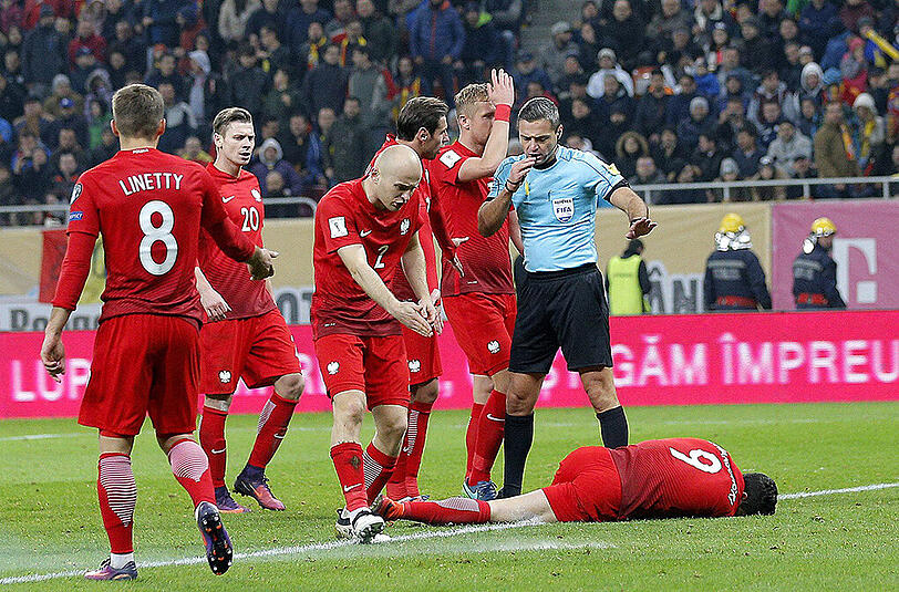 Im WM-Qualispiel gegen Rumänien wurde Polens Kapitän Robert Lewandowski von einem Knallkörper getroffen. Nach kurzer Behandlung spielte der Bayern-Star weiter - und erzielte noch einen Doppelpack. Die Bilder.