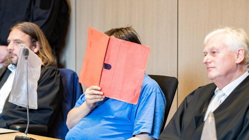 Der Angeklagte zu Beginn seines Prozesses mit einem Aktenmappe vor dem Gesicht im Landgericht im Gerichtssaal zwischen seinen Anwälten. Der Angeklagte zu Beginn seines Prozesses mit einem Aktenmappe vor dem Gesicht im Landgericht im Gerichtssaal zwischen seinen Anwälten.