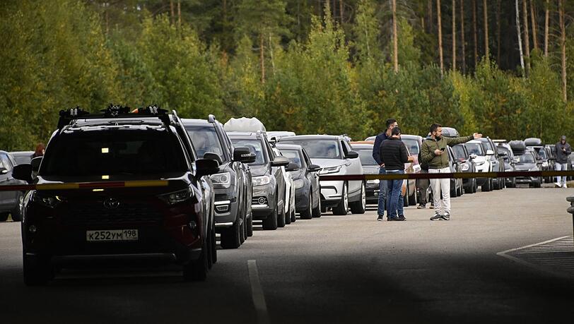 Stoßstange an Stoßstange stehen die Autos an der russischen Grenze zu Finnland. Meist sitzt ein Mann am Steuer.