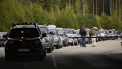 Stoßstange an Stoßstange stehen die Autos an der russischen Grenze zu Finnland. Meist sitzt ein Mann am Steuer.