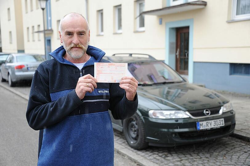 Der Münchner Gerhard Heinke mit seinem Auto und dem Strafzettel, den er partout nicht bezahlen möchte.