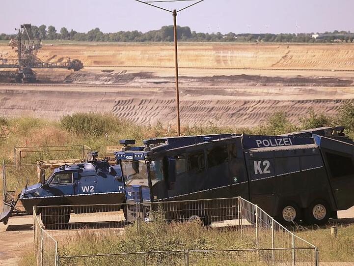 Ein gepanzertes Räumfahrzeug und ein Wasserwerfer der Polizei stehen am Rand des Braunkohle-Tagebaus Garzweiler.