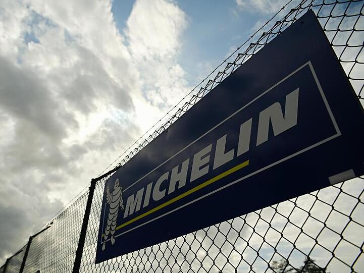 Wolken ziehen über ein Firmenschild von Michelin. Foto: Nicolas Armer/dpa/Archivbild
