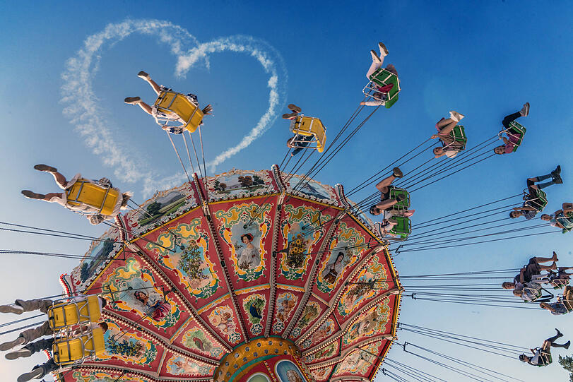 Das Kettenkarussell Wellenflug bei der ersten Fahrt, am Himmel ist noch das Wiesnherz zu erkennen.