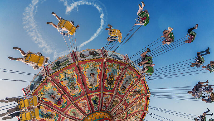 Das Kettenkarussell Wellenflug bei der ersten Fahrt, am Himmel ist noch das Wiesnherz zu erkennen.