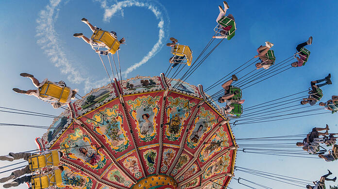 Das Kettenkarussell Wellenflug bei der ersten Fahrt, am Himmel ist noch das Wiesnherz zu erkennen.