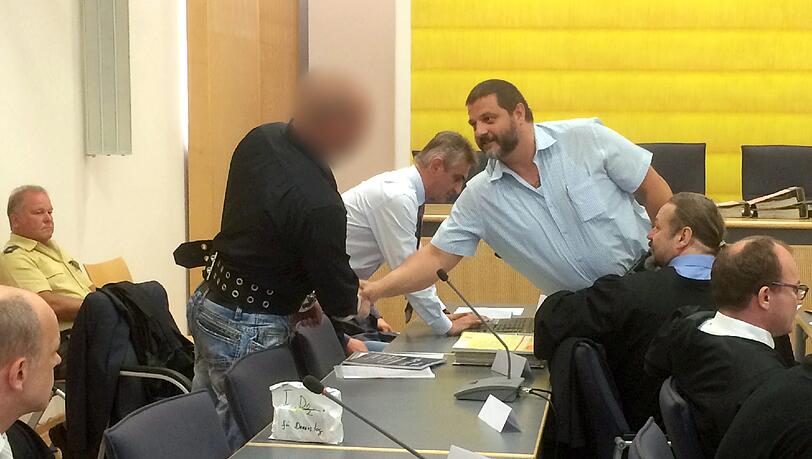 Der Angeklagte Sascha Roßmüller (r.), Vorstandsmitglied der bayerischen NPD, begrüßt im Landgericht Regensburg einen weiteren Angeklagten.