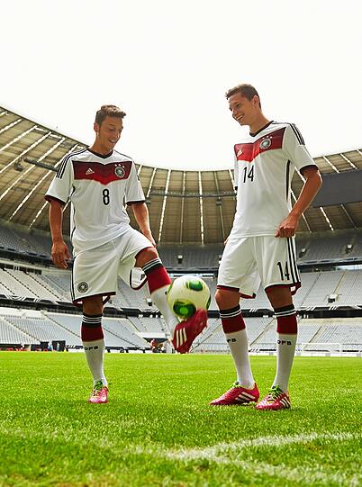 So sieht das WM-Trikot 2014 in Brasilien aus. Mesut Özil (l.) und Julian Draxler führen es in der Allianz Arena schon mal vor. Was auffällt: Der rote Streifen auf der Brust - und die weißen Hosen.
