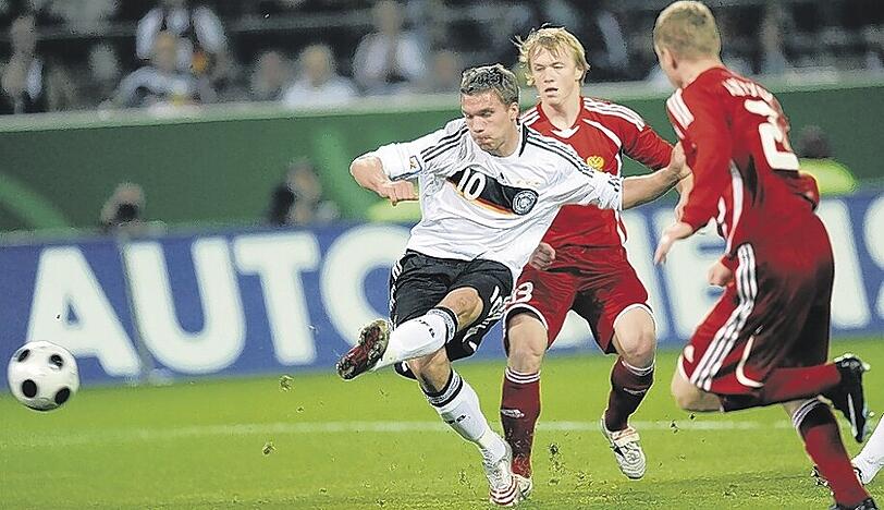 Vorbildliche Schusstechnik: Lukas Podolski beim 1:0, Yanbaew (li.) und Anjukow kommen zu spät.