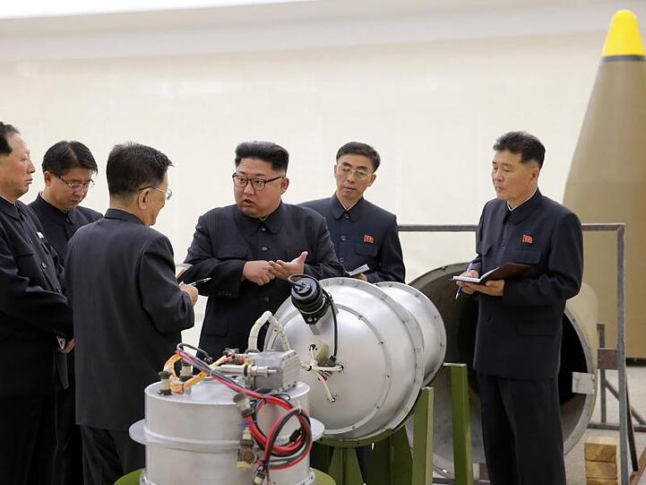Nordkoreas Staatschef Kim Jong Un neben einem Sprengkopf.