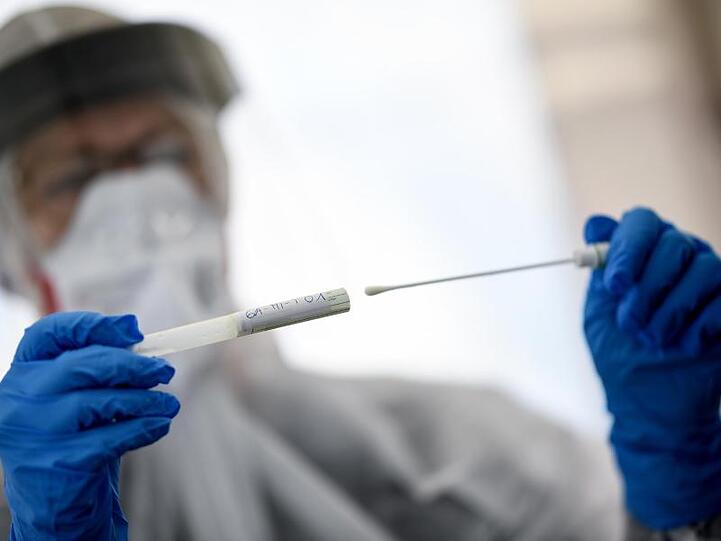 Eine Mitarbeiterin des Gesundheitsamts in Berlin-Mitte hält ein Abstrichstäbchen in einer ambulanten Test-Einrichtung in der Hand.