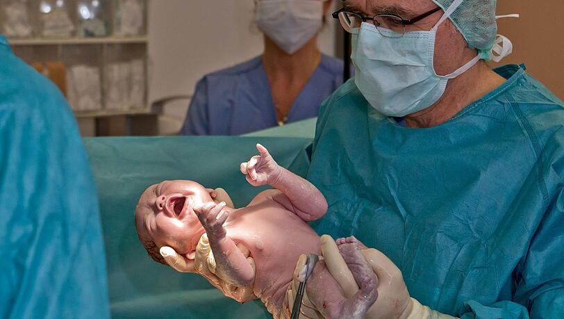 Ein Baby kommt in einem Kreißsaal in Erlangen zur Welt. Die von Gesundheitsminister Karl Lauterbach angestoßene Krankenhausreform könnte unter anderem zur Schließung zahlreicher Geburtshilfestationen führen.