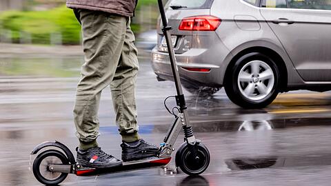 Ein Mann fährt mit einem E-Scooter auf der Straße.