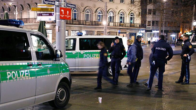Polizisten stehen in der Nacht zum 07.12.2019 am Augsburger Königsplatz am Tatort. Dort war ein 49 Jahre alter Feuerwehrmann bei einer Auseinandersetzung mit Jugendlichen getötet worden.