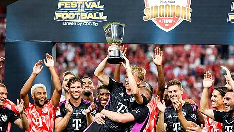 Frans Krätzig (M) hält den Pokal. Der FC Bayern reist im Sommer wieder nach Asien.