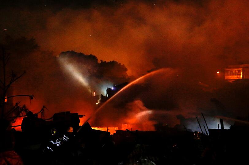 Philippinische Feuerwehrmänner versuchen einen Großbrand in einem Slum östlich von Manila zu löschen.
