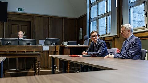 Kay Gottschalk (AfD, M), Bundestagsabgeordneter, sitzt mit Anwalt Michael Zischka (r) und Richter Burkhard Niebisch (hinten l) im Gerichtssaal.