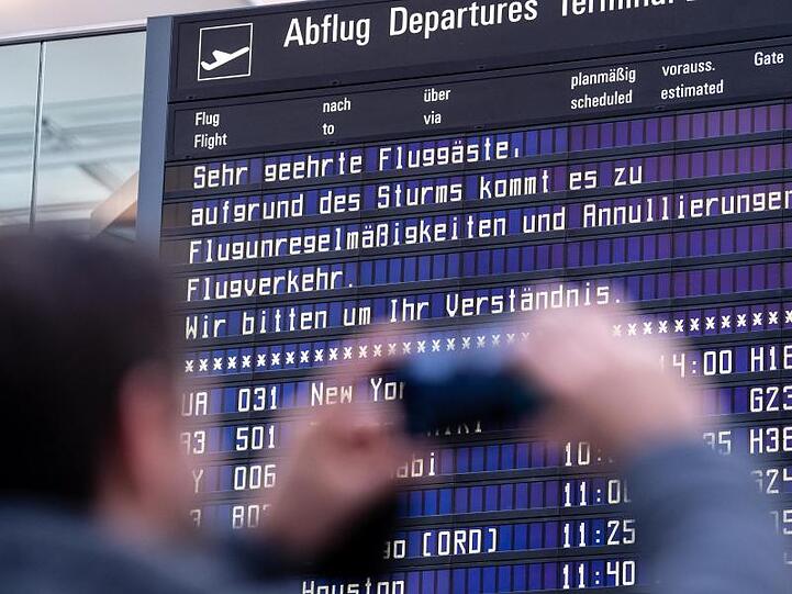 Ein Reisender fotografiert am Münchner Flughafen eine Anzeigetafel. Foto: Matthias Balk/dpa