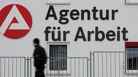 Ein Mann geht an dem Logo der Agentur für Arbeit vorbei.