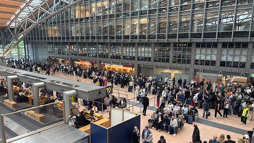 Zahlreiche Menschen stehen im Terminal des Hamburger Flughafens. Zahlreiche Menschen stehen im Terminal des Hamburger Flughafens.