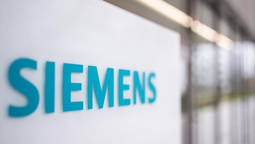 Das Schriftzug-Logo des deutschen Industriekonzerns Siemens, steht auf einer Stele am Eingang eines Bürogebäudes auf dem Siemens Campus Erlangen.