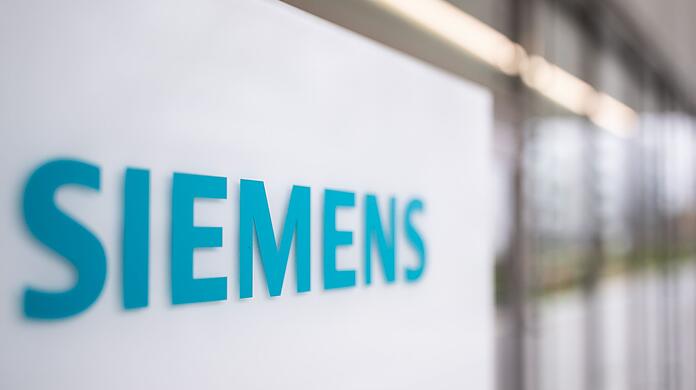 Das Schriftzug-Logo des deutschen Industriekonzerns Siemens, steht auf einer Stele am Eingang eines Bürogebäudes auf dem Siemens Campus Erlangen.