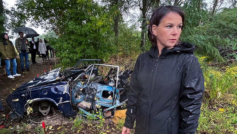 Die deutsche Außenministerin Annalena Baerbock (Bündnis 90/Die Grünen) besichtigt ein von Deutschland gefördertes Minenräumprojekt in der Nähe von Kiew. Das Auto im Hintergrund ist durch eine Mine zerstört worden.